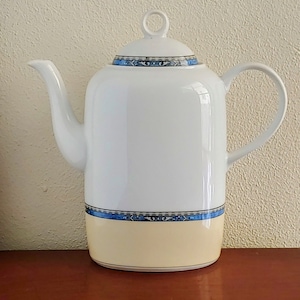 May include: White ceramic coffee pot with a blue and gold trim. The pot has a lid with a knob on top.