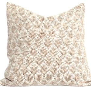 May include: A beige and white throw pillow with a geometric pattern. The pillow is made of a textured fabric and has a square shape.