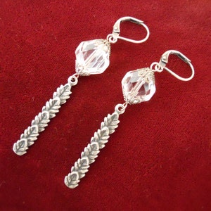 May include: A pair of silver dangle earrings with clear crystal beads and a leaf design.