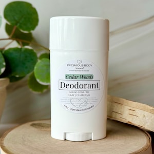 White deodorant stick with a label that reads 'PRESHIOUS BODY Natural HANDCRAFTED SKINCARE Cedar Woods Deodorant BAKING SODA FREE CLAY | CHARCOAL *etsy @preshiousbodynatural'