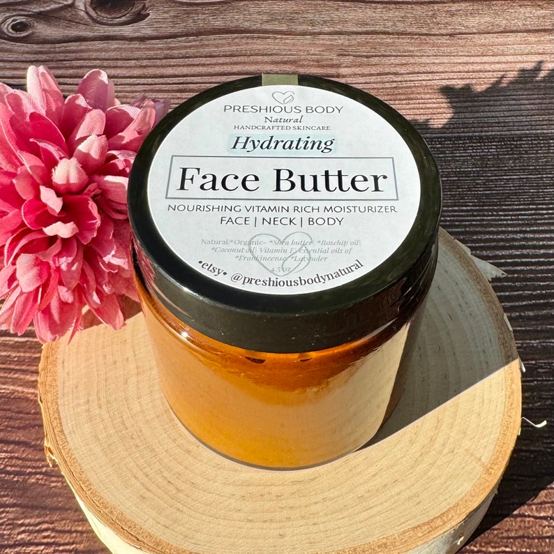 May include: A glass jar with a black lid filled with a face butter. The jar has a white label with the text 'PRESHIOUS BODY', 'Natural', 'HANDCRAFTED SKINCARE', 'Hydrating', 'Face Butter', 'NOURISHING VITAMIN RICH MOISTURIZER', 'FACE | NECK | BODY', 'Natural Organic Shea butter Rosehip oil Coconut Vitamin E Essential oils of Frankincense Lavender', 'etsy. @preshiousbodynatural'.