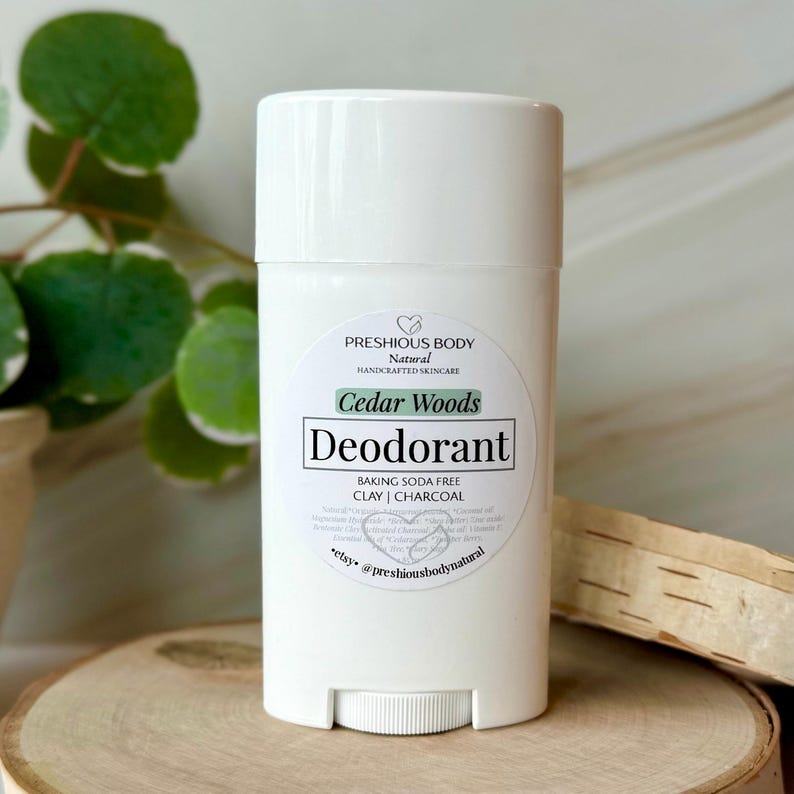 A deodorant stick with a label that reads 'PRESHIOUS BODY Natural HANDCRAFTED SKINCARE Cedar Woods Deodorant BAKING SODA FREE CLAY | CHARCOAL *etsy @preshiousbodynatural'