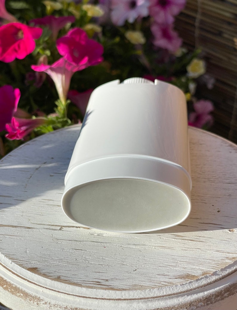 A white deodorant tube stick with a gray product. The deodorant stick is on a white wooden surface.