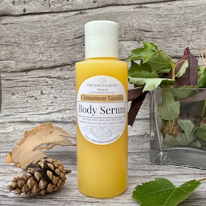 A bottle of body serum with a white label. The label says 'Preshious Body Natural Handcrafted Skincare Cinnamon Vanilla Body Serum Nourishing Antioxidant Rich Moisturizer for Soft Smooth Skin *ctay @preshiousbodynatural'