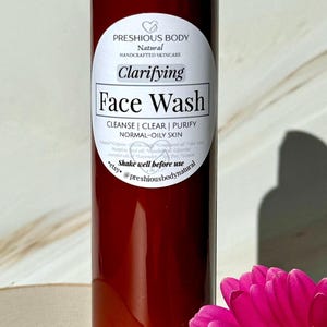 A brown bottle of clarifying face wash with a white label that reads 'Preshious Body Natural Handcrafted Skincare Clarifying Face Wash Cleanse | Clear | Purify Normal-Oily Skin Shake well before use etsy @preshiousbodynatural'.