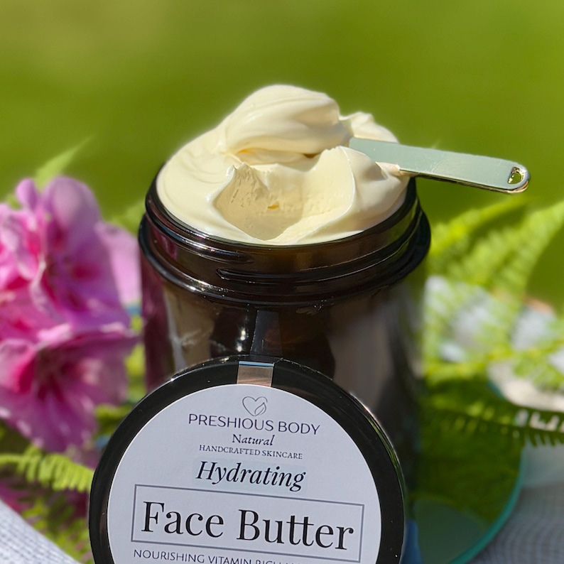 May include: A glass jar with a black lid filled with a face butter. The jar has a white label with the text 'PRESHIOUS BODY', 'Natural', 'HANDCRAFTED SKINCARE', 'Hydrating', 'Face Butter', 'NOURISHING VITAMIN RICH MOISTURIZER', 'FACE | NECK | BODY', 'Natural Organic Shea butter Rosehip oil Coconut Vitamin E Essential oils of Frankincense Lavender', 'etsy. @preshiousbodynatural'.