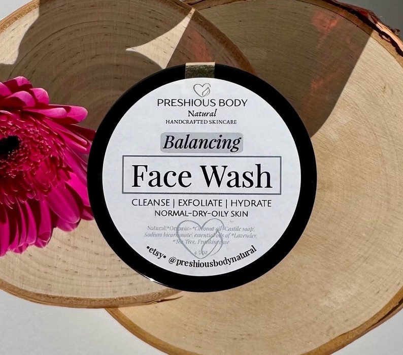 Puede incluir: Un tarro negro con una etiqueta blanca que dice "PRESHIOUS BODY Natural HANDCRAFTED SKINCARE Balancing Face Wash CLEANSE | EXFOLIATE | HYDRATE NORMAL-DRY-OILY SKIN Natural *Organic* Coconut oil, Castile soap, Sodium bicarbonate, essential oils of Lavender, Tea Tree, Frankincense etsy @preshiousbodynatural"