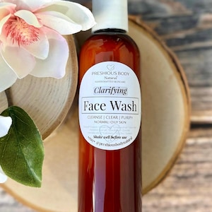 A brown bottle of clarifying face wash with a white label that reads 'Preshious Body Natural Handcrafted Skincare Clarifying Face Wash Cleanse | Clear | Purify Normal-Oily Skin Shake well before use etsy @preshiousbodynatural'.