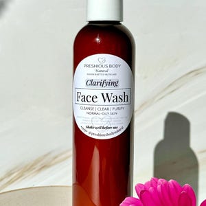 A brown bottle of clarifying face wash with a white label that reads 'Preshious Body Natural Handcrafted Skincare Clarifying Face Wash Cleanse | Clear | Purify Normal-Oily Skin Shake well before use etsy @preshiousbodynatural'.