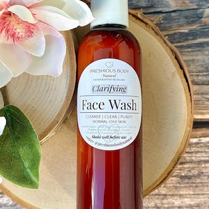 A brown bottle of clarifying face wash with a white label that reads 'Preshious Body Natural Handcrafted Skincare Clarifying Face Wash Cleanse | Clear | Purify Normal-Oily Skin Shake well before use etsy @preshiousbodynatural'.