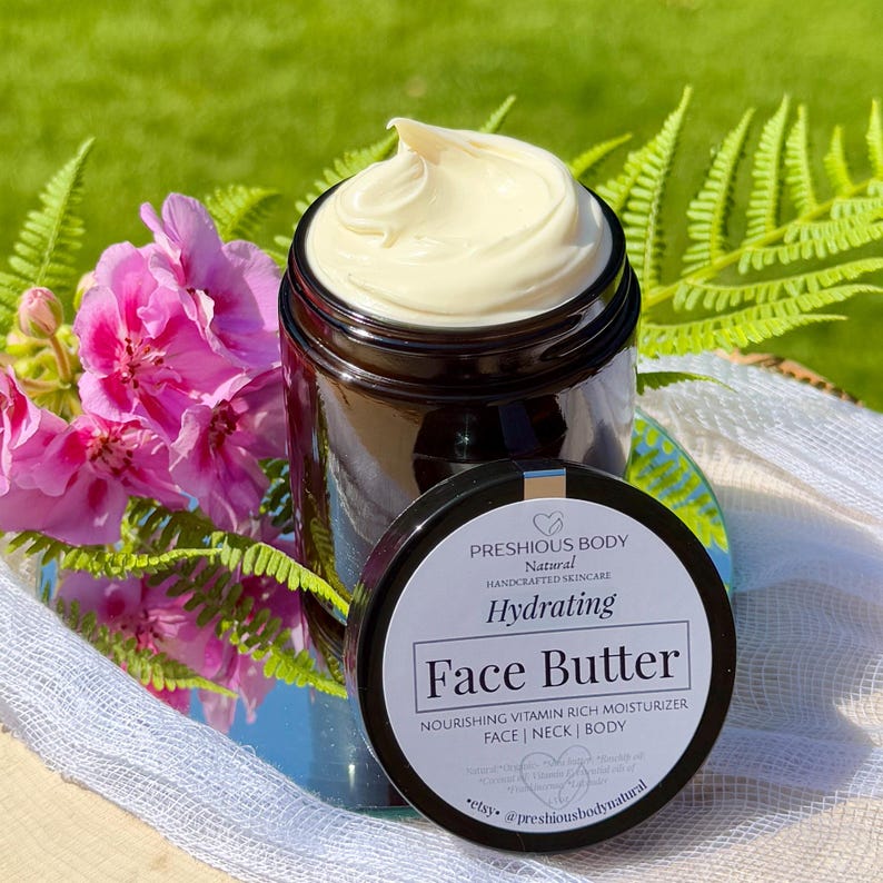 May include: A glass jar with a black lid filled with a face butter. The jar has a white label with the text 'PRESHIOUS BODY', 'Natural', 'HANDCRAFTED SKINCARE', 'Hydrating', 'Face Butter', 'NOURISHING VITAMIN RICH MOISTURIZER', 'FACE | NECK | BODY', 'Natural Organic Shea butter Rosehip oil Coconut Vitamin E Essential oils of Frankincense Lavender', 'etsy. @preshiousbodynatural'.