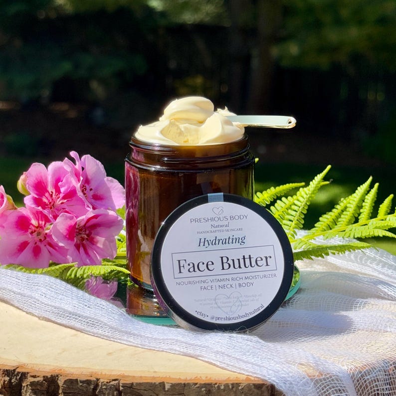 May include: A glass jar with a black lid filled with a face butter. The jar has a white label with the text 'PRESHIOUS BODY', 'Natural', 'HANDCRAFTED SKINCARE', 'Hydrating', 'Face Butter', 'NOURISHING VITAMIN RICH MOISTURIZER', 'FACE | NECK | BODY', 'Natural Organic Shea butter Rosehip oil Coconut Vitamin E Essential oils of Frankincense Lavender', 'etsy. @preshiousbodynatural'.