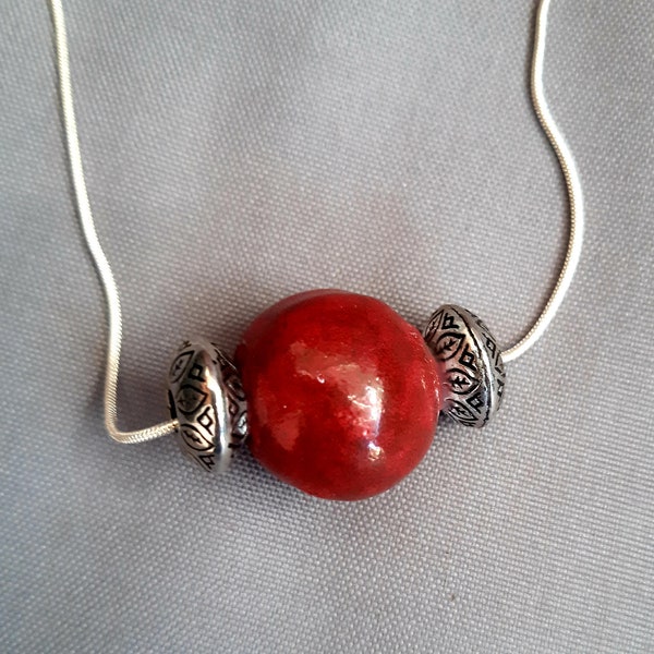 Pendentif "boule" en céramique rouge fait main encadrée par des perles argent tibétain, sur une chaîne en plaqué argent