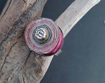 Bague avec un cabochon en papier recyclé et vernis, dans des tons multicolores avec au centre une petite fleur en argent tibétain.