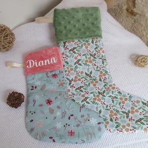 K&ouml;nnte beinhalten: Zwei Weihnachtsstr&uuml;mpfe mit einem gr&uuml;n-wei&szlig;en Blumenmuster. Ein Strumpf hat einen rosa Bund mit dem Namen "Diana" bestickt. Der andere Strumpf hat einen gr&uuml;nen Pl&uuml;schbund.