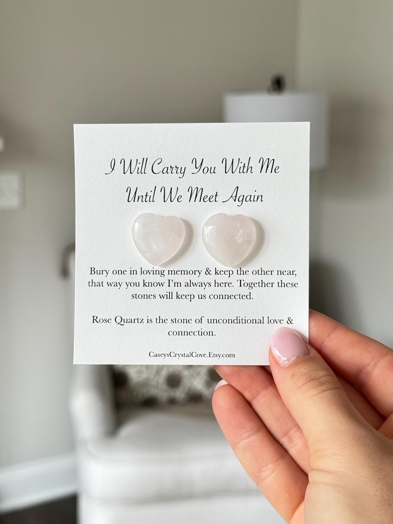 Puede incluir: Dos peque&ntilde;as piedras de cuarzo rosa en forma de coraz&oacute;n rosa sobre una tarjeta blanca con el texto "I Will Carry You With Me Until We Meet Again". La tarjeta tambi&eacute;n incluye el texto "Bury one in loving memory & keep the other near, that way you know I'm always here. Together these stones will keep us connected. Rose Quartz is the stone of unconditional love & connection. CaseysCrystalCove.Etsy.com"