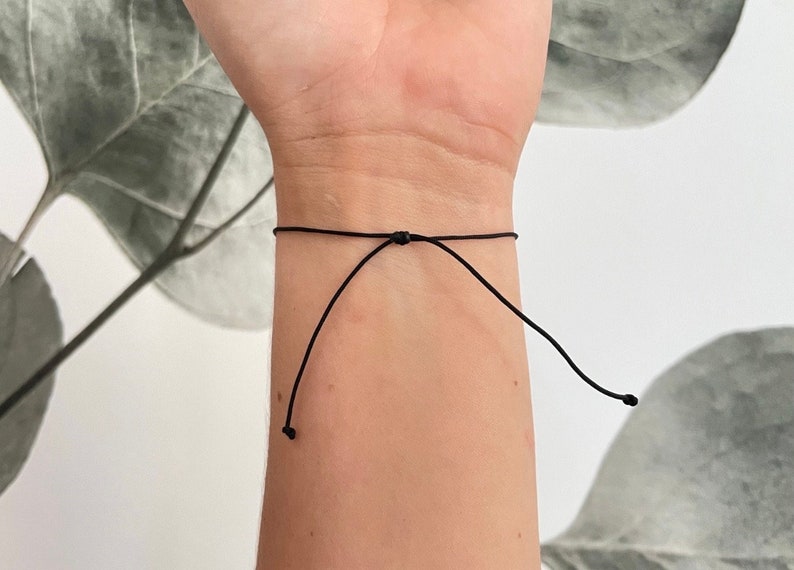 May include: A black adjustable bracelet made of thin cord.