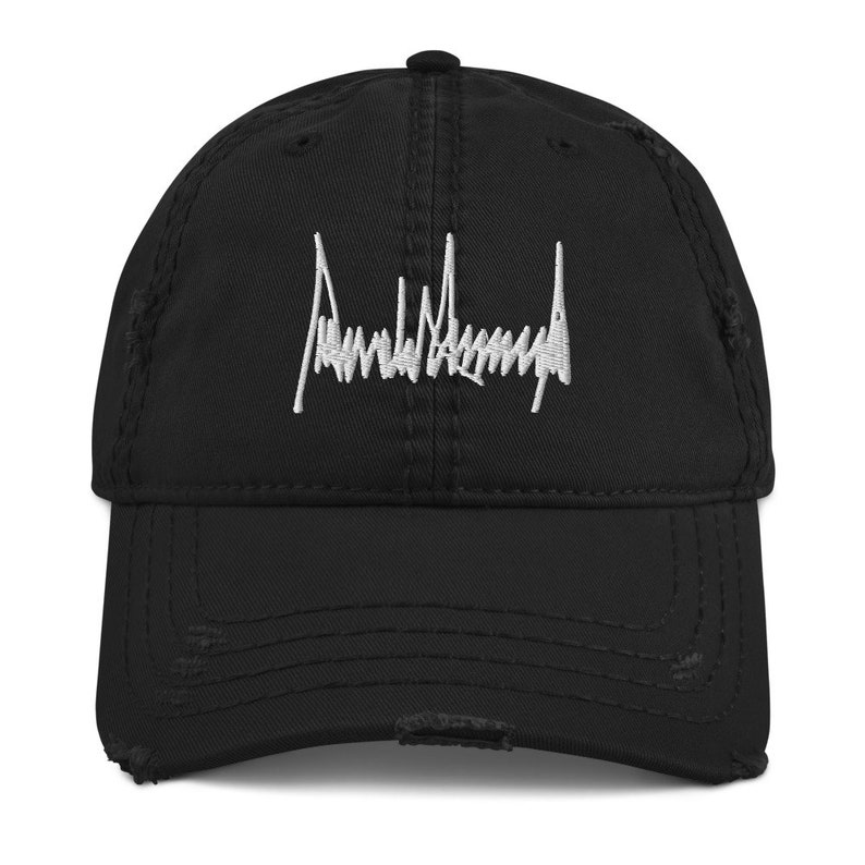 Peut inclure: Une casquette de baseball noire us&eacute;e avec une signature brod&eacute;e blanche qui lit "Donald Trump".