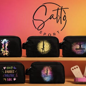 Peut inclure: Cinq trousses de toilette rectangulaires noires avec fermetures éclair et poignées latérales. Chaque trousse présente un imprimé graphique unique lié à la gymnastique, incluant des silhouettes d'athlètes et le texte SAUT BARRES POUTRE SOL.