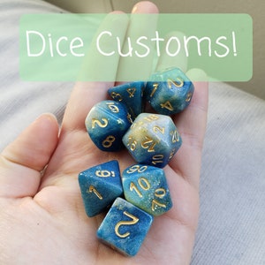 May include: A set of seven blue and gold dice with white and gold flecks. The dice are in a hand, with the text "Dice Customs!" above them.