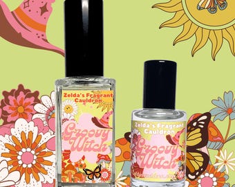 May include: Two perfume bottles with black lids, labelled "Zelda's Fragrant Cauldron" and "Groovy Witch." The labels have a pink and orange design with a witch's hat, mushrooms, and a butterfly. The background is light green with floral and sun illustrations.