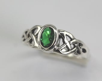 May include: A silver ring with a green gemstone set in a Celtic knot design.