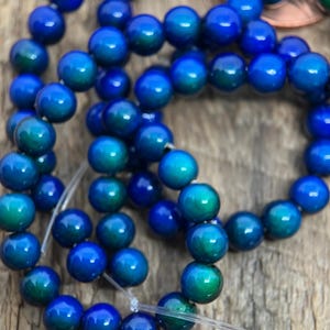 Puede incluir: Hebras de cuentas azules y turquesas. Las cuentas son redondas y tienen un acabado brillante. Las cuentas están ensartadas en un hilo transparente. El color de las cuentas pasa del azul al turquesa.