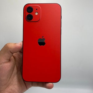 May include: A red smartphone with a matte finish featuring a black Apple logo centered on the back panel. The device has a dual-camera system arranged vertically in the top left corner, including a flash and two circular lenses with black rims.
