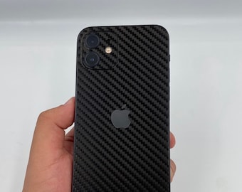 May include: Black iPhone with a carbon fiber pattern on the back. The phone has a black Apple logo and a triple camera system.