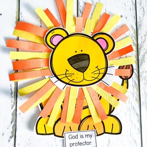 May include: A yellow lion with a black outline and orange and yellow mane. The lion is sitting on a white surface with a sign that says "God is my protector."