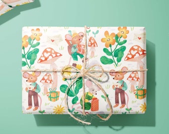 Puede incluir: Un regalo rectangular envuelto en papel blanco con un patrón repetitivo de ratones de dibujos animados, setas rojas con puntos blancos, flores amarillas, sobres con corazones rojos y regalos, atado con un cordel de yute marrón natural.