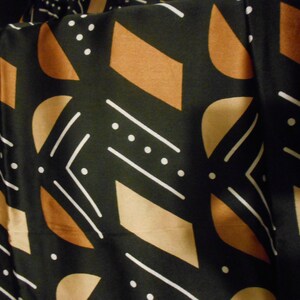Puede incluir: Tela negra con un patr&oacute;n geom&eacute;trico de l&iacute;neas blancas, formas marrones y tostadas y puntos blancos.