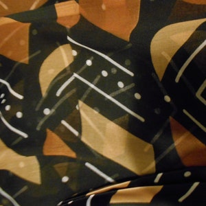 Puede incluir: Tela con estampado abstracto en negro, marr&oacute;n y blanco. La tela tiene un dise&ntilde;o geom&eacute;trico con formas y l&iacute;neas superpuestas.