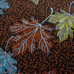 Peut inclure: Gros plan sur un tissu avec un motif de feuilles répétées. Les feuilles sont dans des tons d'orange, de jaune et de bleu, avec des veines blanches, sur un fond marron foncé avec un motif tourbillonnant. Idéal pour les vêtements ou la décoration intérieure.