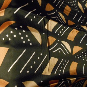 Puede incluir: Tela negra con un patr&oacute;n geom&eacute;trico de l&iacute;neas blancas, formas marrones y beige y puntos blancos.