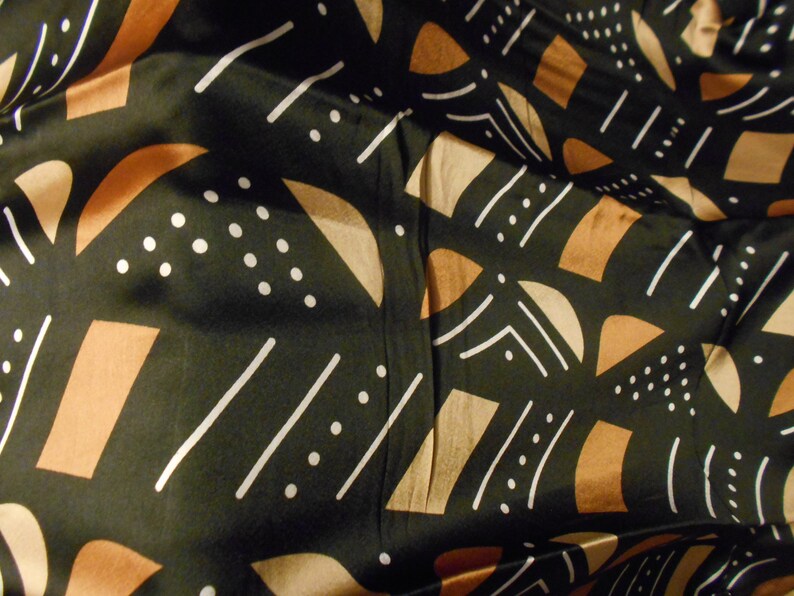 Puede incluir: Tela negra con un patr&oacute;n geom&eacute;trico de l&iacute;neas blancas, formas marrones y beige y puntos blancos.