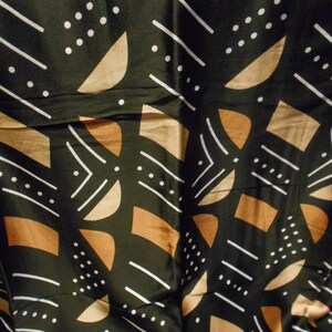 Puede incluir: Tela negra con un patr&oacute;n geom&eacute;trico en marr&oacute;n y blanco. El patr&oacute;n incluye c&iacute;rculos, l&iacute;neas y semic&iacute;rculos.