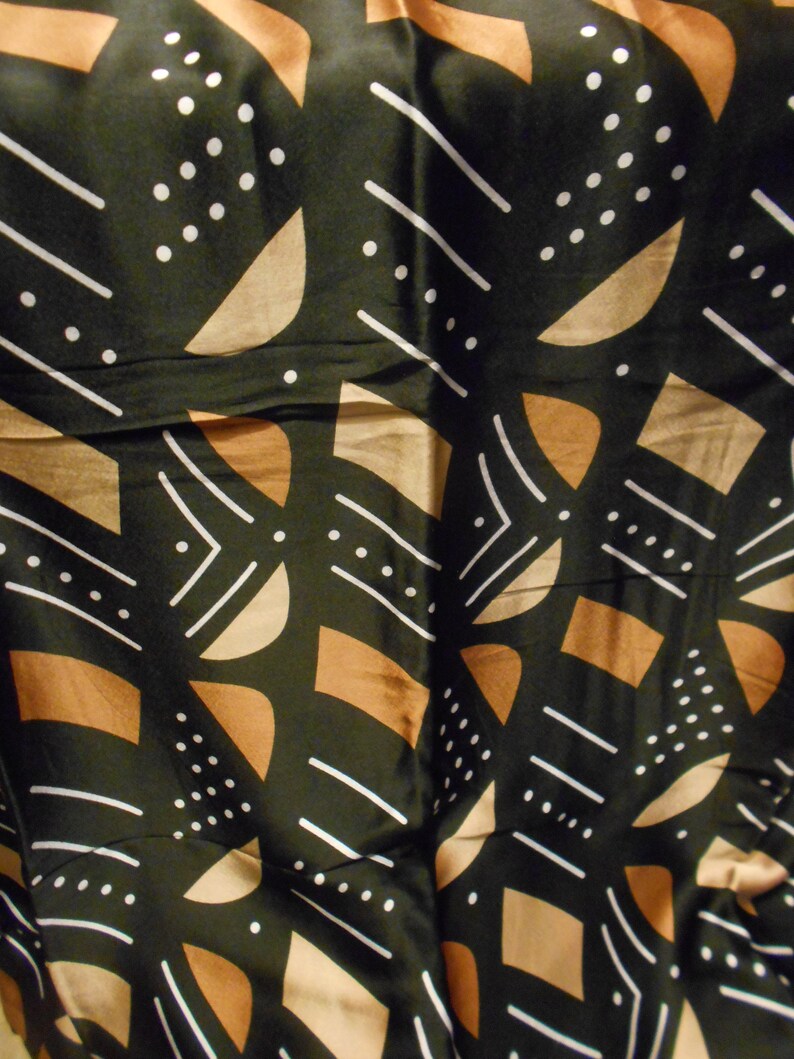 Puede incluir: Tela negra con un patr&oacute;n geom&eacute;trico en marr&oacute;n y blanco. El patr&oacute;n incluye c&iacute;rculos, l&iacute;neas y semic&iacute;rculos.