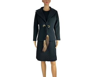 May include: A black quilted skirt suit with a fur trim and gold accents. The jacket has a notched collar and a tie closure with gold rings.
