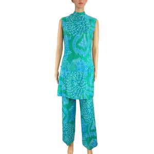 May include: A sleeveless, high-neck tunic and matching pants set. The outfit features a vibrant teal and turquoise pattern with white accents. The tunic falls to mid-thigh, and the pants are wide-legged. The fabric appears lightweight, suitable for warmer weather.