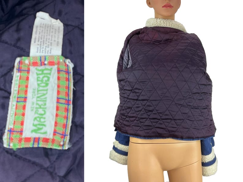 K&ouml;nnte beinhalten: Gesteppte marineblaue Jacke mit cremefarbenem Shearling-Kragen. Die Jacke hat blaue Jeans&auml;rmel mit cremefarbenen Streifen und eine cremefarbene Shearling-Manschette. Ein Etikett mit dem Markennamen "Mackintosh New York" ist sichtbar.