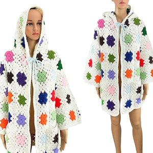 May include: White crochet cardigan with a colorful granny square pattern and a hood. The cardigan has a tie closure at the neck.