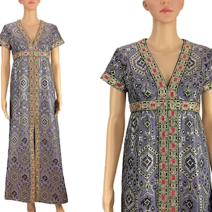 Puede incluir: Un vestido largo de color morado y dorado con estampado geométrico y detalles en rosa. Tiene cuello en V y mangas cortas.