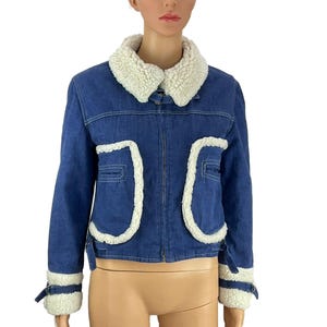 K&ouml;nnte beinhalten: Blaue Jeansjacke mit cremefarbenem Kunstfellkragen und -besatz. Die Jacke hat zwei Vordertaschen und einen Rei&szlig;verschluss. Die Manschetten sind ebenfalls mit cremefarbenem Kunstfell besetzt. Eine stilvolle und warme Oberbekleidung.