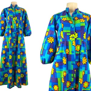Puede incluir: Un vestido azul de manga larga con un estampado geométrico y floral colorido. El vestido tiene un frente abotonado y una cintura fruncida.