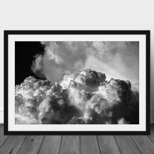 Peut inclure: Une photographie en noir et blanc d'une grande formation nuageuse et moelleuse sur un fond de ciel sombre. Les nuages sont éclairés par derrière, créant un effet dramatique.
