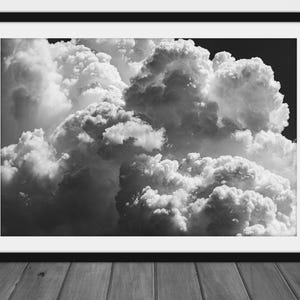 May include: A black and white photograph of a large, fluffy cloud formation in the sky. The clouds are dense and appear to be moving quickly.