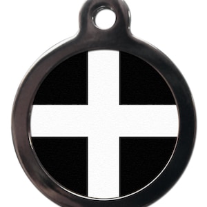 May include: A round, silver-colored pet tag featuring the Cornish flag. The flag design consists of a white cross on a black background. The tag has a hole at the top for attachment to a collar.