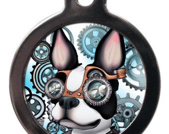 Peut inclure: Une médaille ronde en argent avec un Boston Terrier noir et blanc portant des lunettes steampunk et une sangle en cuir marron. Le chien est entouré d'engrenages bleus et argentés.