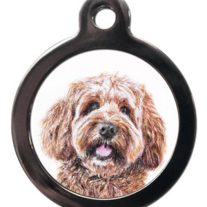 May include: A round, silver dog tag featuring a brown and white dog's face. The dog has its tongue sticking out.